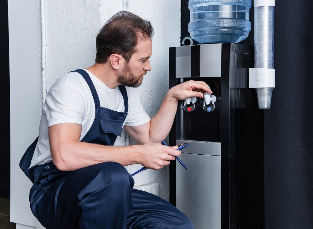 Ein Wasserspendertechniker installiert einen neuen Wasserspenderautomaten bei einem Kunden